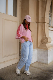 Pull à manches trois-quarts porté par une femme, vue de face, casquette rose, escalier