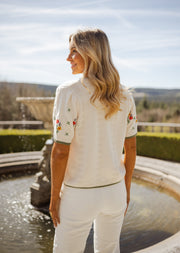 Pull fleuri à manches courtes porté par une femme, vue de dos, fontaine, paysage