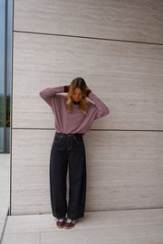 Pull rayé effet cachemire porté par une femme, vue de face, mur beige, mains dans les cheveux