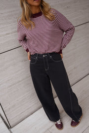 Pull rayé effet cachemire porté par une femme, vue de face, mur beige, jean noir