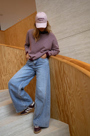 Pull rayé effet cachemire porté par une femme, vue de face, escalier en bois, jean clair