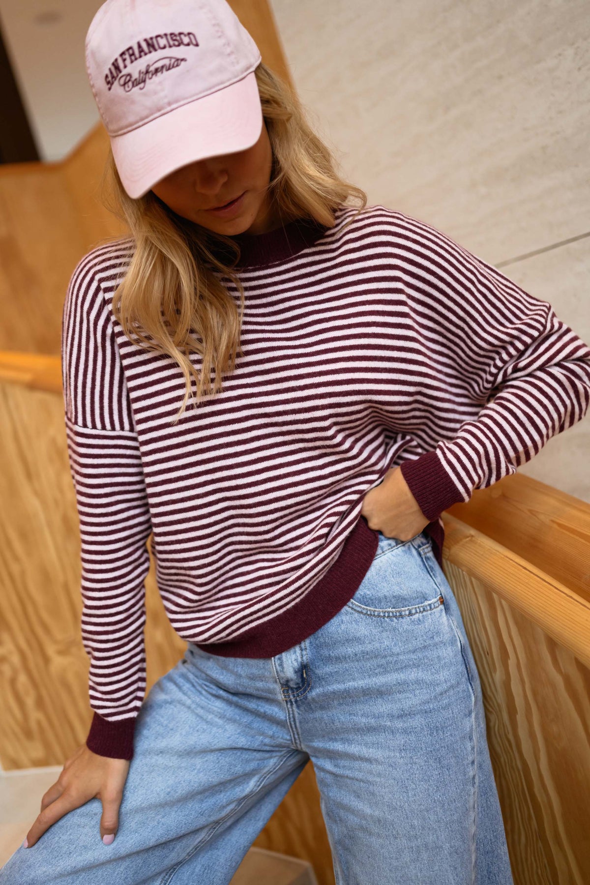 Pull rayé effet cachemire porté par une femme, vue de trois-quarts, casquette rose, jean clair