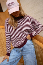 Pull rayé effet cachemire porté par une femme, vue de trois-quarts, casquette rose, jean clair