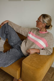 Pull rayé doux col rond porté par une femme, allongée sur un pouf