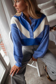 Pull à col montant boutonné bleu porté par une femme, vue rapprochée, chevrons blancs, chaise