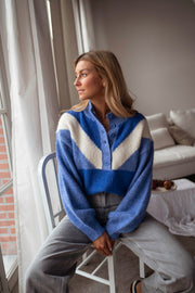 Pull à col montant boutonné bleu porté par une femme, vue de face, chaise, jean