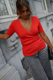 Pull cache-cœur manches courtes porté par une femme, vue rapprochée, main sur la hanche, jean gris