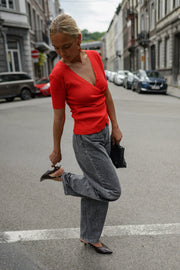 Pull cache-cœur manches courtes porté par une femme, en marchant, jean gris, jambe levée, rue