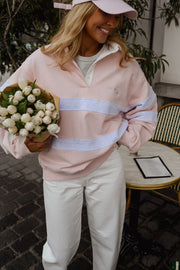 Pull ample à col polo porté par une femme, vue rapprochée, casquette rose, bouquet de fleurs blanches