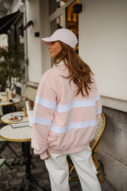 Pull ample à col polo porté par une femme, vue de dos, casquette rose, terrasse