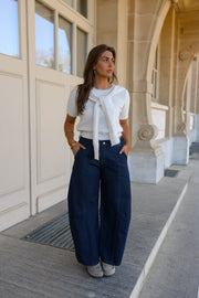 Pull à revers amovible porté par une femme, silhouette entière, pantalon bleu marine, devant une porte vitrée