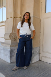 Pull à revers amovible porté par une femme, silhouette entière, pantalon bleu marine, devant une colonne