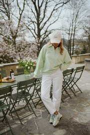 Pull à col boutonné porté par une femme, en marchant, casquette, terrasse