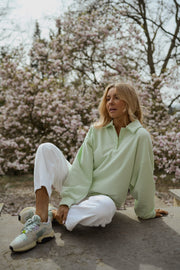 Pull à col boutonné porté par une femme, assise, sur le sol, magnolias, baskets