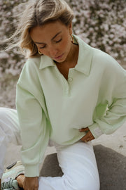 Pull à col boutonné porté par une femme, vue rapprochée, magnolias, pantalon blanc