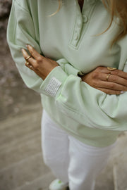 Pull à col boutonné porté par une femme, gros plan de la manche et du col