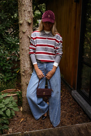 Pull rayé à col polo porté par une femme, vue de face, tronc d'arbre, sac bordeaux