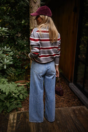Pull rayé à col polo porté par une femme, vue de face, tronc d'arbre, jean large