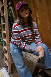 Pull rayé à col polo porté par une femme, assise, échelle en bois, casquette bordeaux