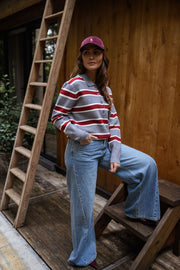 Pull rayé à col polo porté par une femme, vue de trois-quarts, échelle en bois, casquette