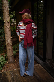 Pull rayé à col polo porté par une femme, vue de face, écharpe bordeaux, casquette
