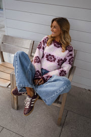 Pull à fleurs col rond porté par une femme, assise, chaise en bois, jean clair