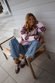 Pull à fleurs col rond porté par une femme, assise, chaise en bois, baskets bordeaux