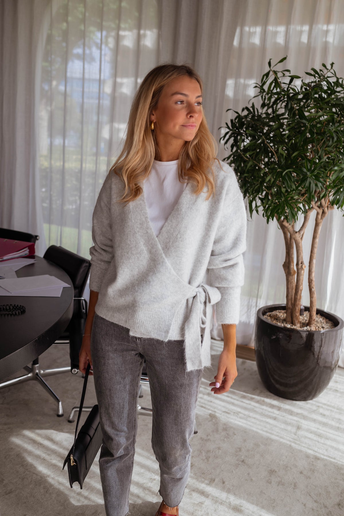 Pull cache-cœur à nouer gris porté par une femme, vue de face, plante, cache-cœur noué