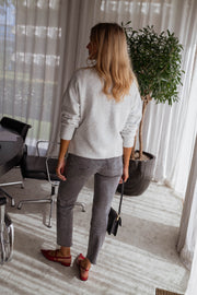 Pull cache-cœur à nouer gris porté par une femme, vue de dos, plante, sac noir