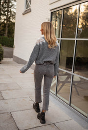 Pull à perles col rond gris porté par une femme, vue de dos, jean gris, terrasse