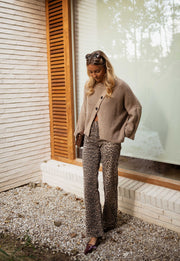Pull boutonné col rond taupe porté par une femme, silhouette entière, fenêtre, pantalon gris