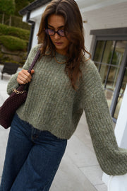 Pull doux à manches ballon porté par une femme, vue de trois-quarts, lunettes, sac bordeaux