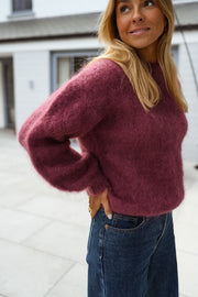 Pull ample aubergine col rond porté par une femme, vue rapprochée, maille aubergine, jean foncé