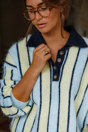 Pull ample à col boutonné bleu clair et crème à rayures porté par une femme, vue rapprochée, lunettes
