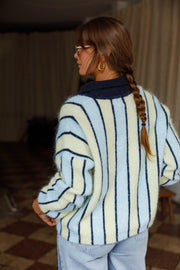 Pull ample à col boutonné bleu clair et crème à rayures porté par une femme, vue de dos