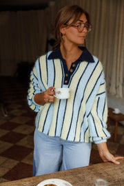 Pull ample à col boutonné bleu clair et crème à rayures porté par une femme, vue de face, tasse à la main