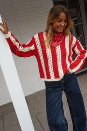 Pull ajouré à col rond porté par une femme, vue de trois-quarts, poteau blanc, bandana rouge