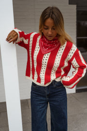 Pull ajouré à col rond porté par une femme, vue rapprochée, bandana rouge, bras levé