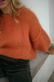 Pull col rond manches trois-quarts orange porté par une femme, vue rapprochée, maille orange, manche bouffante
