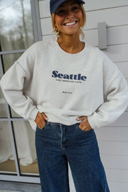 Pull ample à logo porté par une femme, vue de face, logo Seattle, mains dans les poches
