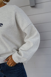 Pull ample à logo porté par une femme, vue rapprochée, manche large, main dans la poche