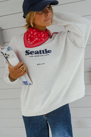 Pull ample à logo porté par une femme, vue de trois-quarts, casquette marine, bandana rouge