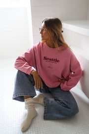 Pull loose à col rond porté par une femme, assise, sol blanc, chaussettes