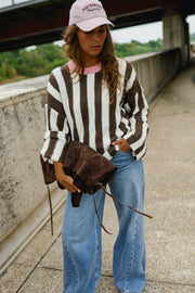 Pull rayé manches évasées porté par une femme, silhouette entière, sac marron à la main