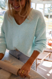 Pull col V manches longues porté par une femme, vue rapprochée, col V, cuisine