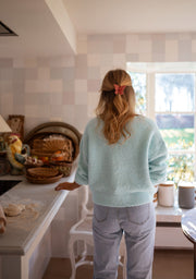 Pull col V manches longues porté par une femme, vue de dos, cuisine, jean clair