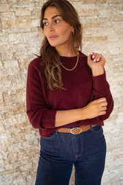 Pull doux légèrement court bordeaux porté par une femme, vue rapprochée, collier, ceinture marron