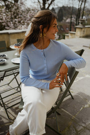 Pull boutonné à manches longues porté par une femme, assise, sur une chaise de jardin, vue de face
