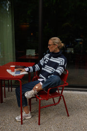 Pull doux avec écharpe porté par une femme, assise, sur une chaise rouge