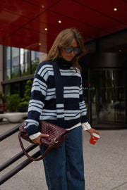 Pull doux avec écharpe porté par une femme, silhouette entière, sac à la main, en terrasse